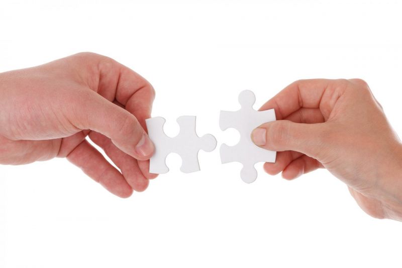 Zwei Hände halten jeweils ein Puzzleteil